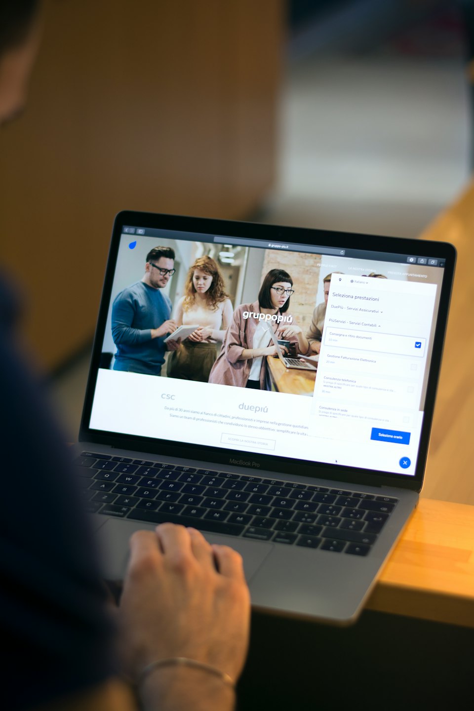 Osoba pisząca na srebrnym laptopie MacBook Pro w pomieszczeniu.