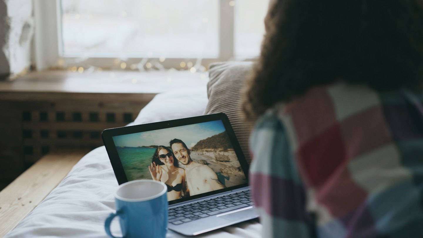 Osoba oglądająca zdjęcie pary na ekranie laptopa.